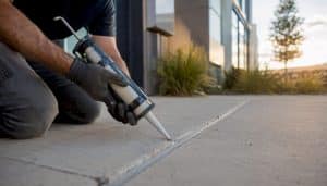 Hands applying sealant to concrete expansion joint