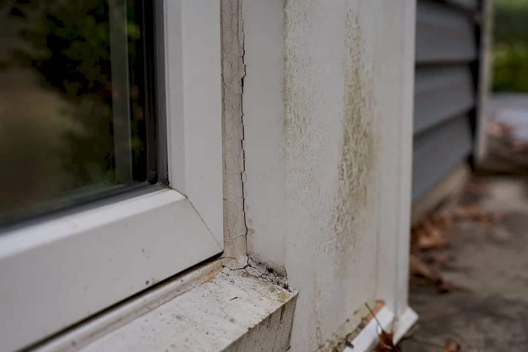 Cracked caulking and water damage near window frame