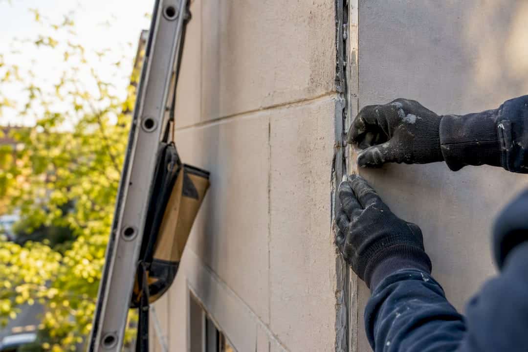 Hands inspecting weatherstripping on building door frame