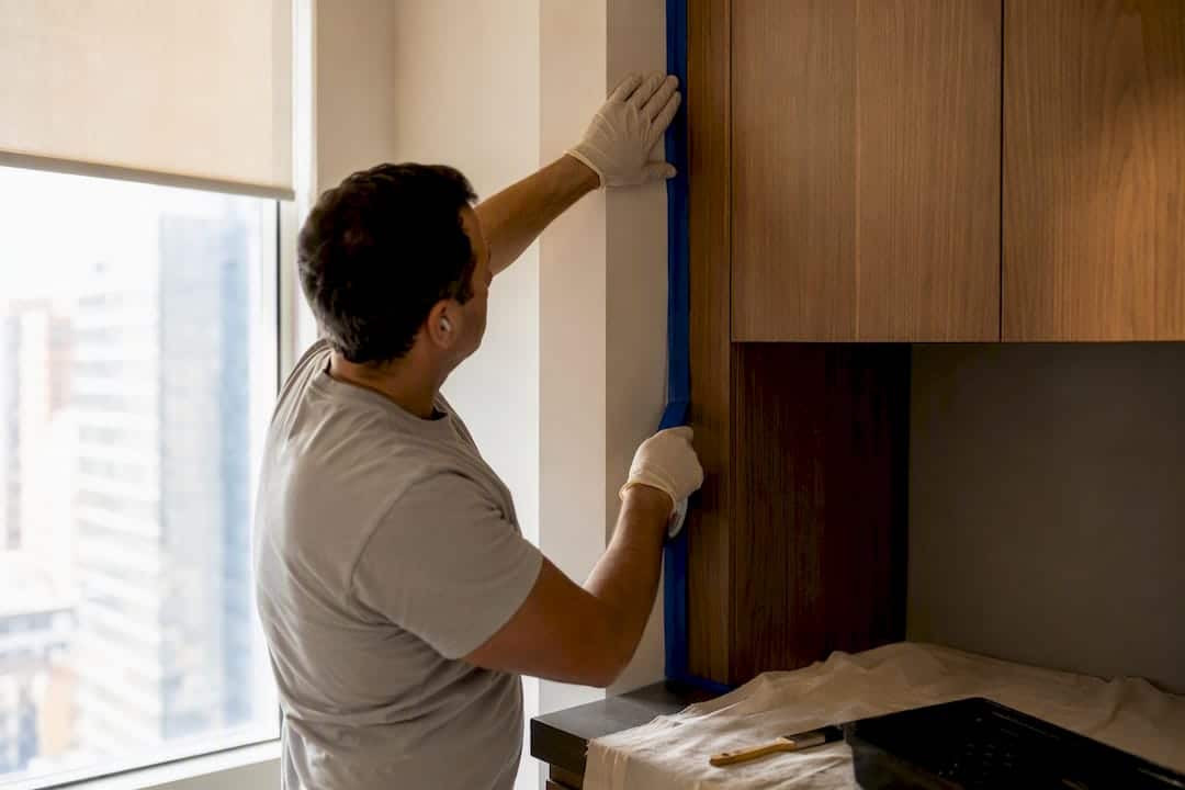 Painter applying painter's tape on wall edge