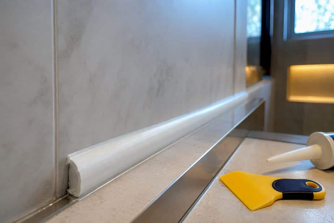 Fresh caulk bead curing in tiled shower