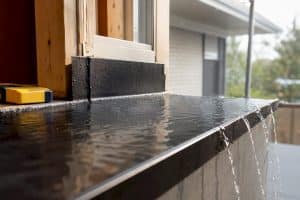 Window sill pan directing water outward