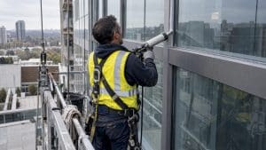 Technician sealing a glass curtain wall joint