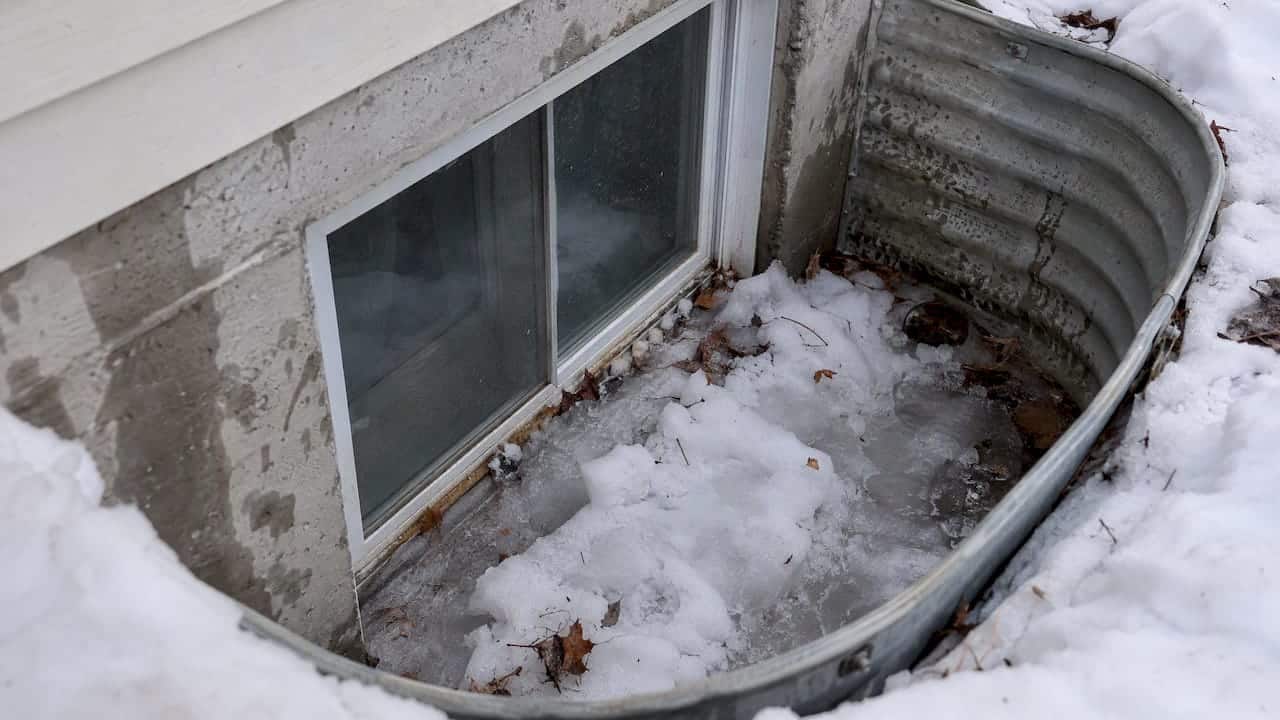 Snow and ice gathered in a basement window well